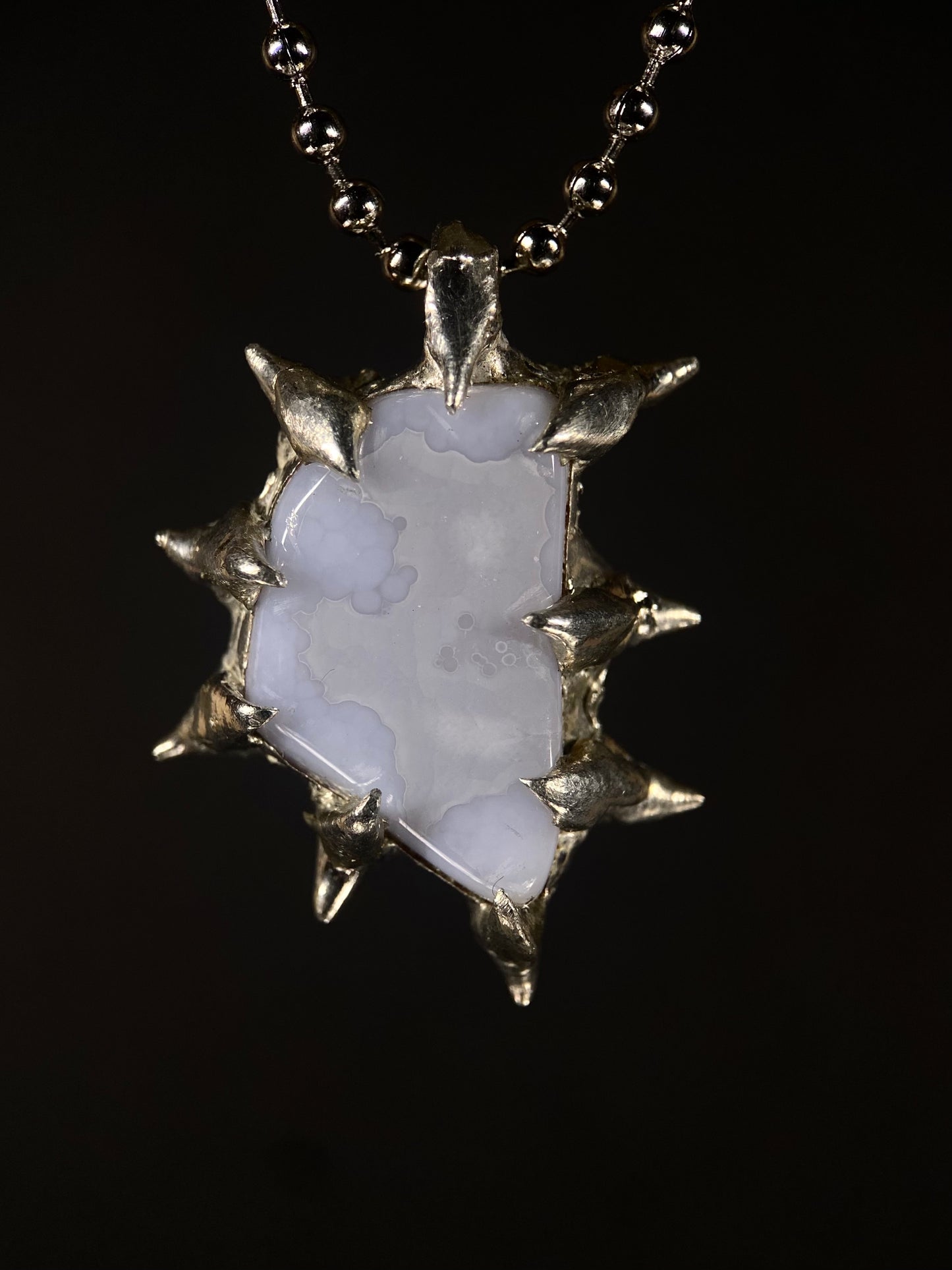 Close-up of handmade spiky Blue Chalcedony pendant with sterling silver setting, calming crystal, artisan jewelry design