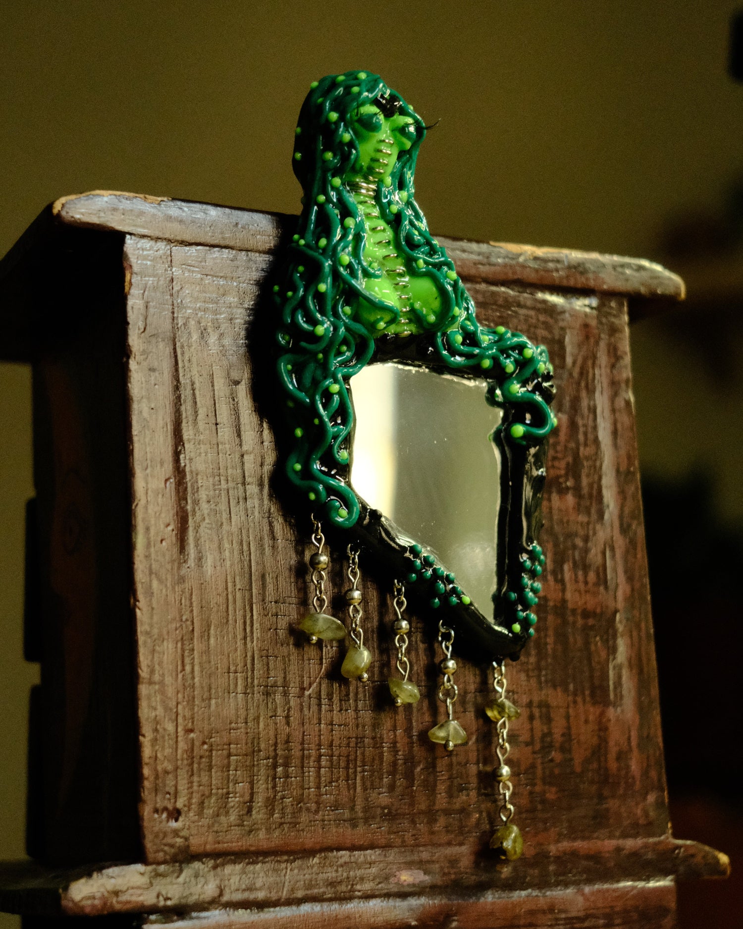 alien siren mirror hanging on the back of wooden chest