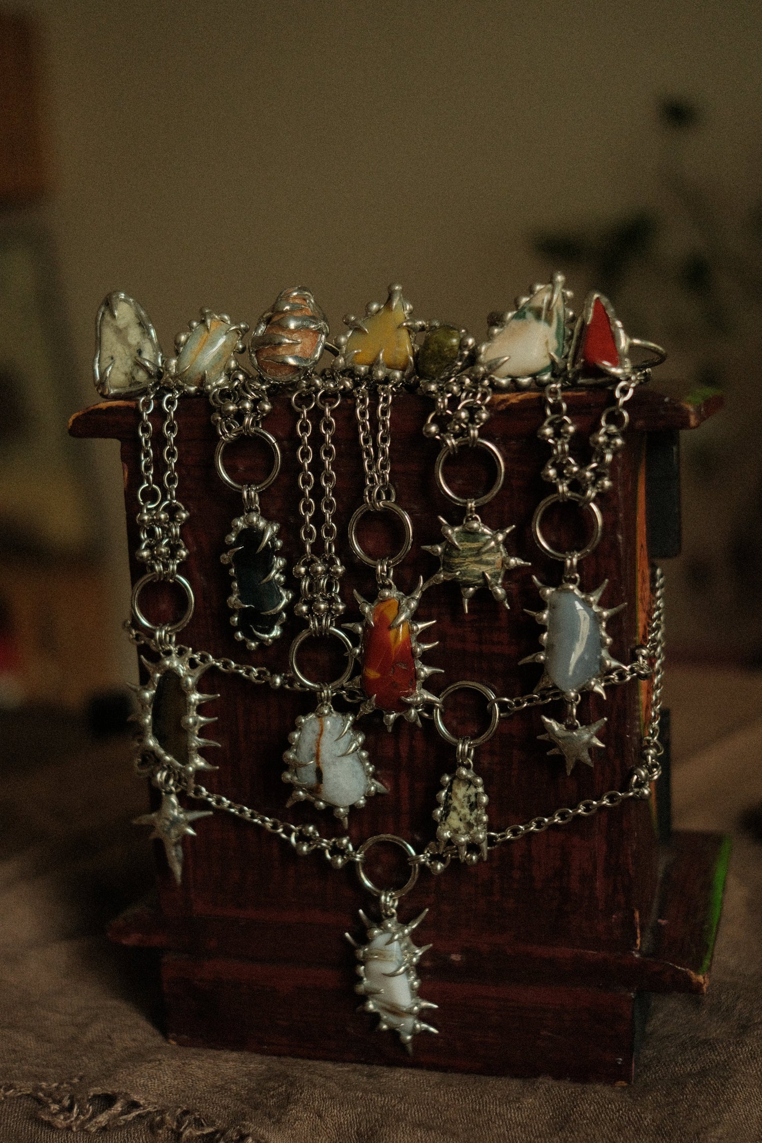 spiky grunge crystals jewelry, all the necklaces and rings with gemstones wrapped aroud a wooden chest