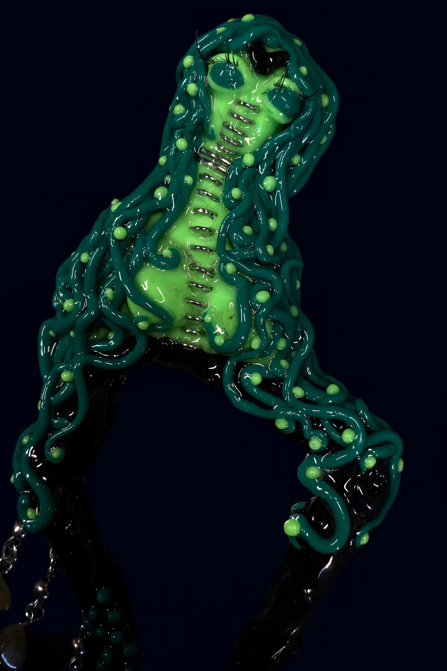 close-up of alien face and upper tentacle details, bright green sculpted polymer clay sealed in glossy resin on dark blue background