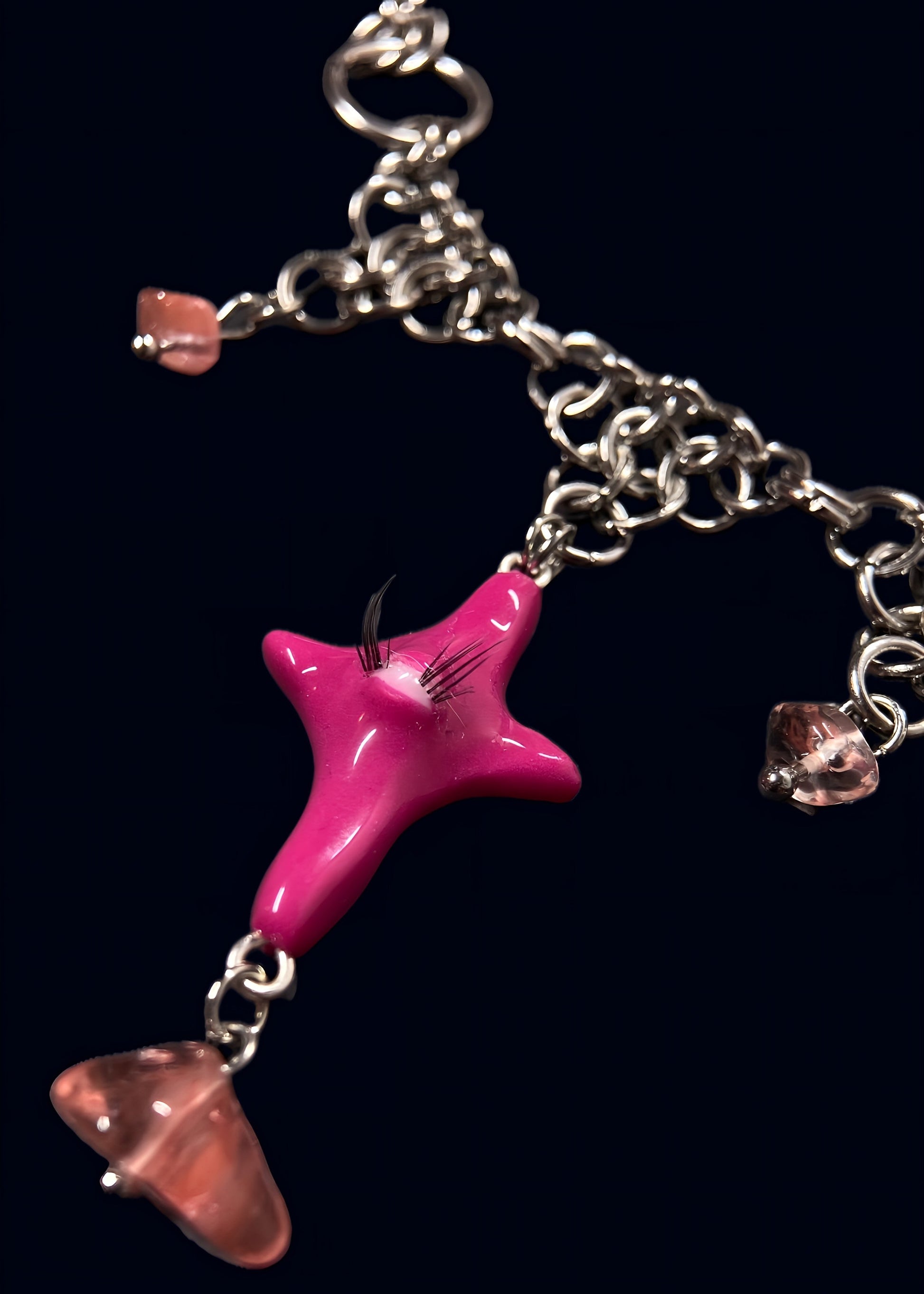 angled detail of pink gazing star necklace highlighting circular metal connectors, chainmail layering and scattered rose quartz chip beads