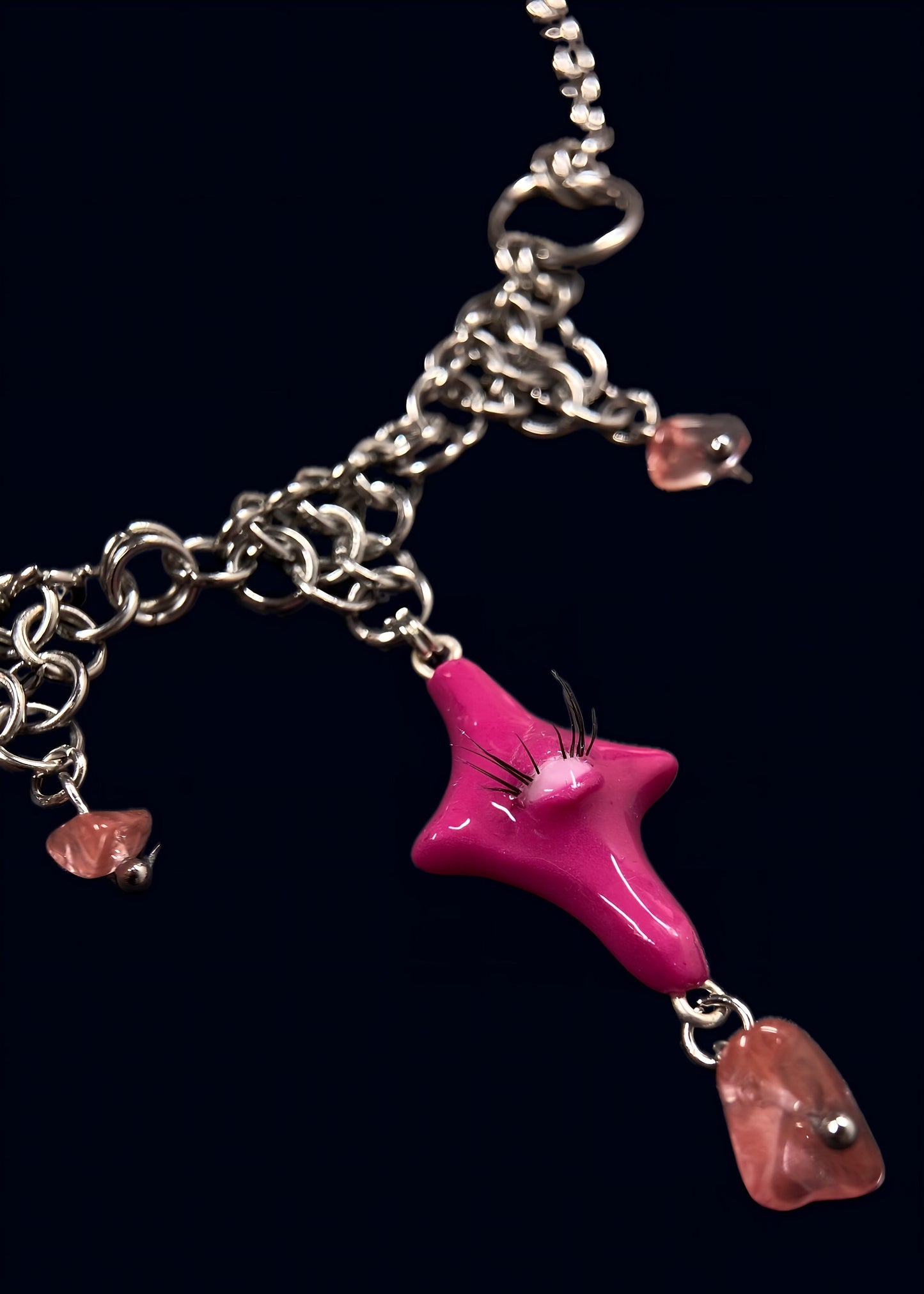 product photo of pink gazing star necklace showing smaller pink star charm connected to layered stainless steel chainmail with rose quartz bead drops