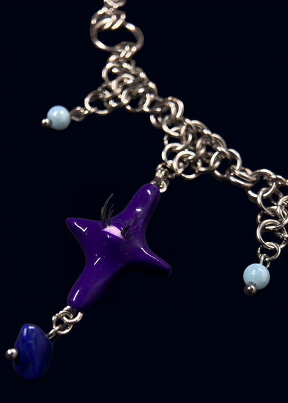 detail photo of purple gazing star necklace showing layered stainless steel chainmail, light blue bead accents and smaller purple star charm