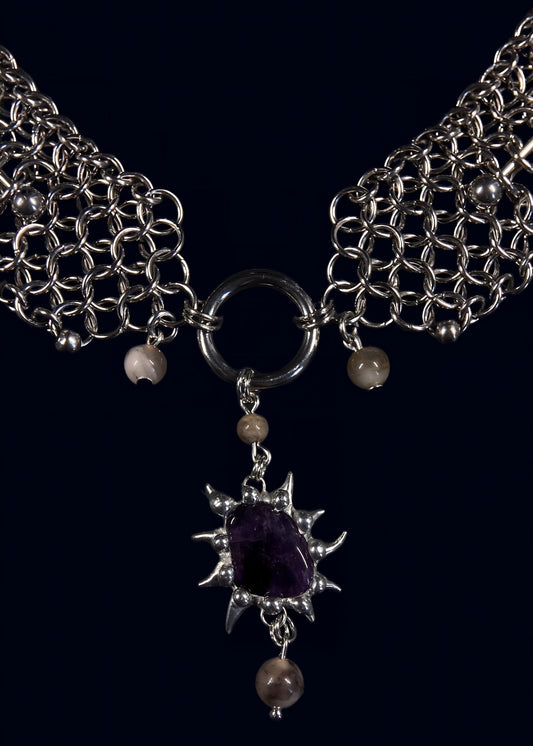 close-up of chainmail shoulder panels joining into a large o-ring holding an amethyst spiked soft solder pendant