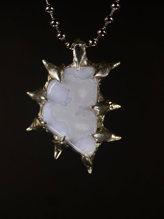 Close-up of handmade spiky Blue Chalcedony pendant with sterling silver setting, calming crystal, artisan jewelry design