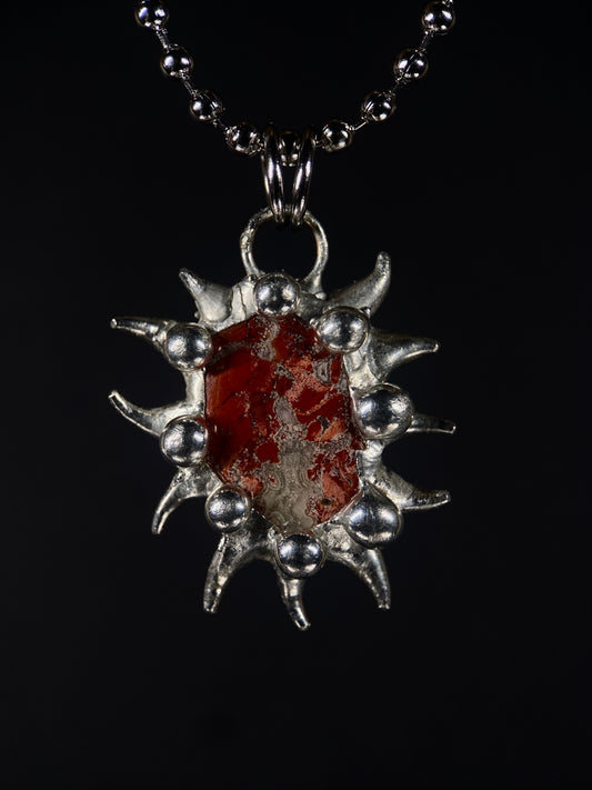 Close-up of handmade spiky Brecciated Jasper pendant in sterling silver, red gemstone with natural patterns, fair trade artisan jewelry