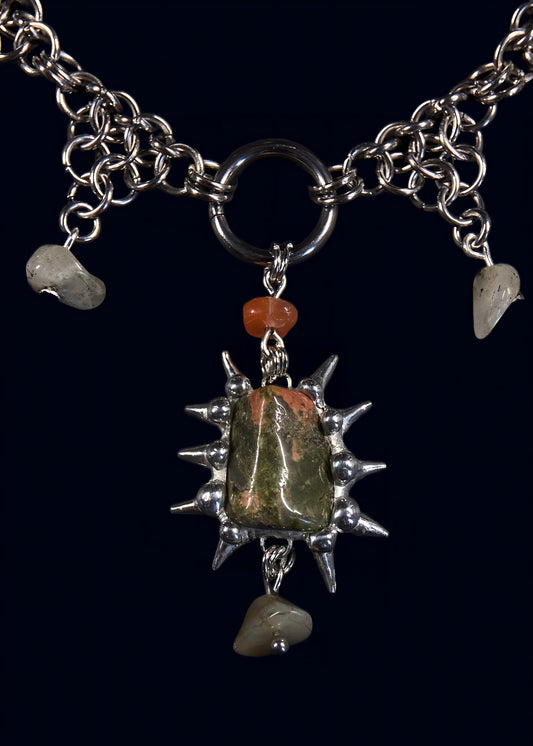 close-up of unakite gemstone framed in hand-formed spiked soft solder setting hanging from chunky o-ring on stainless steel chain with small unakite dangles
